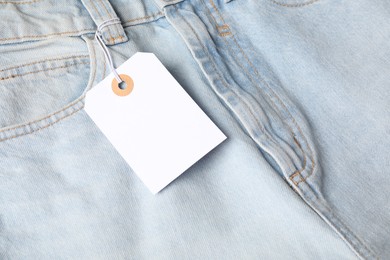 Photo of Cardboard tag on light blue jeans, above view