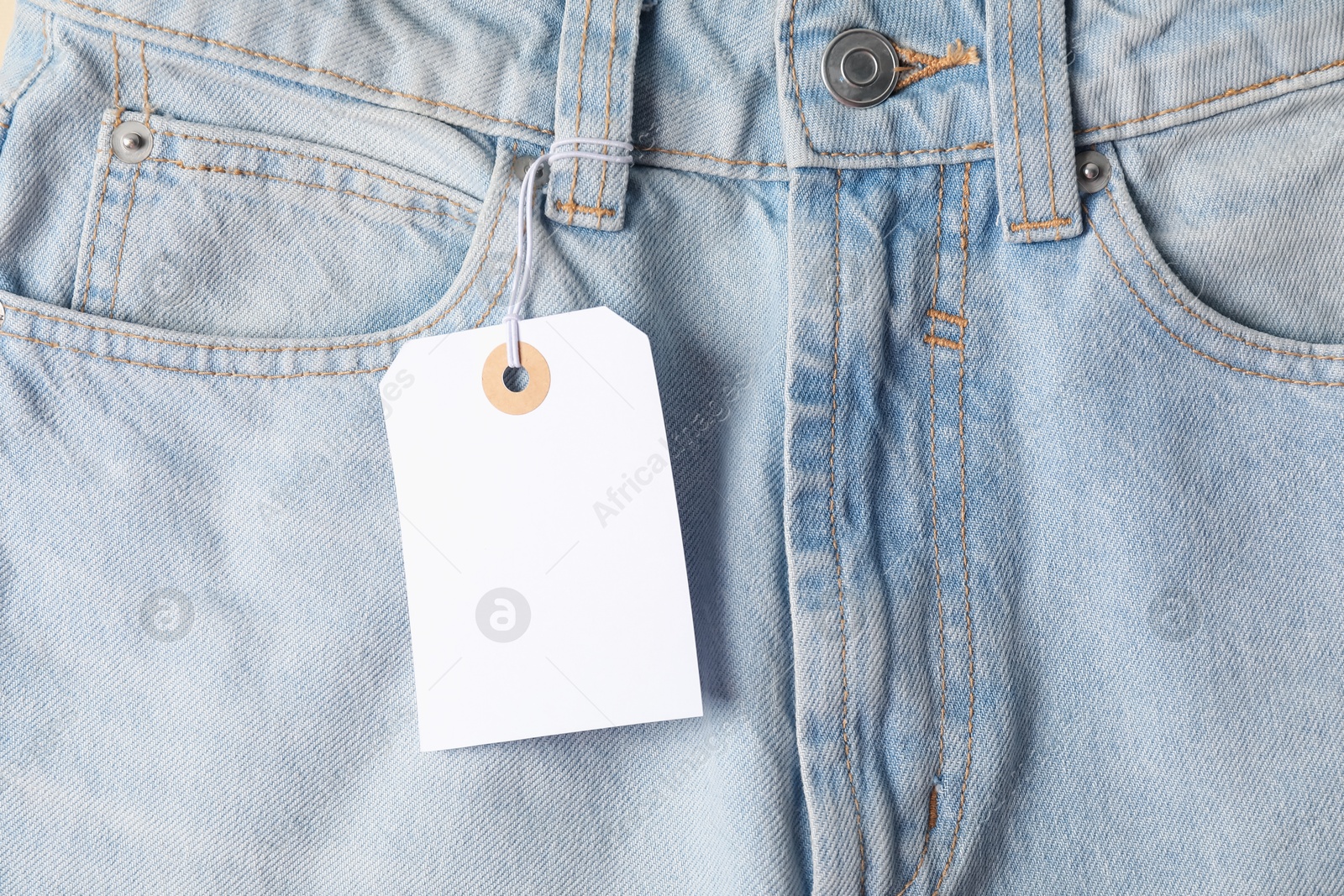 Cardboard tag on light blue jeans, top view Photo of Cardboard tag on light blue jeans, top view
