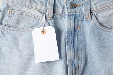 Photo of Cardboard tag on light blue jeans, top view