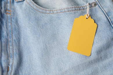 Photo of Cardboard tag on light blue jeans, top view