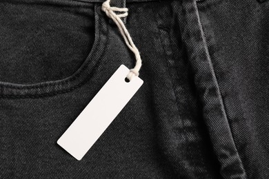 Photo of Cardboard tag on black jeans, top view