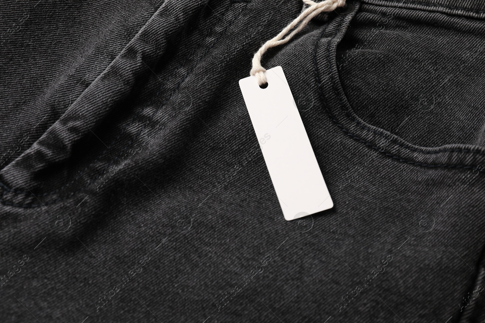 Cardboard tag on black jeans, above view Photo of Cardboard tag on black jeans, above view