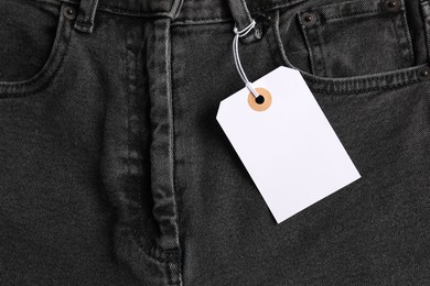Photo of Cardboard tag on black jeans, top view