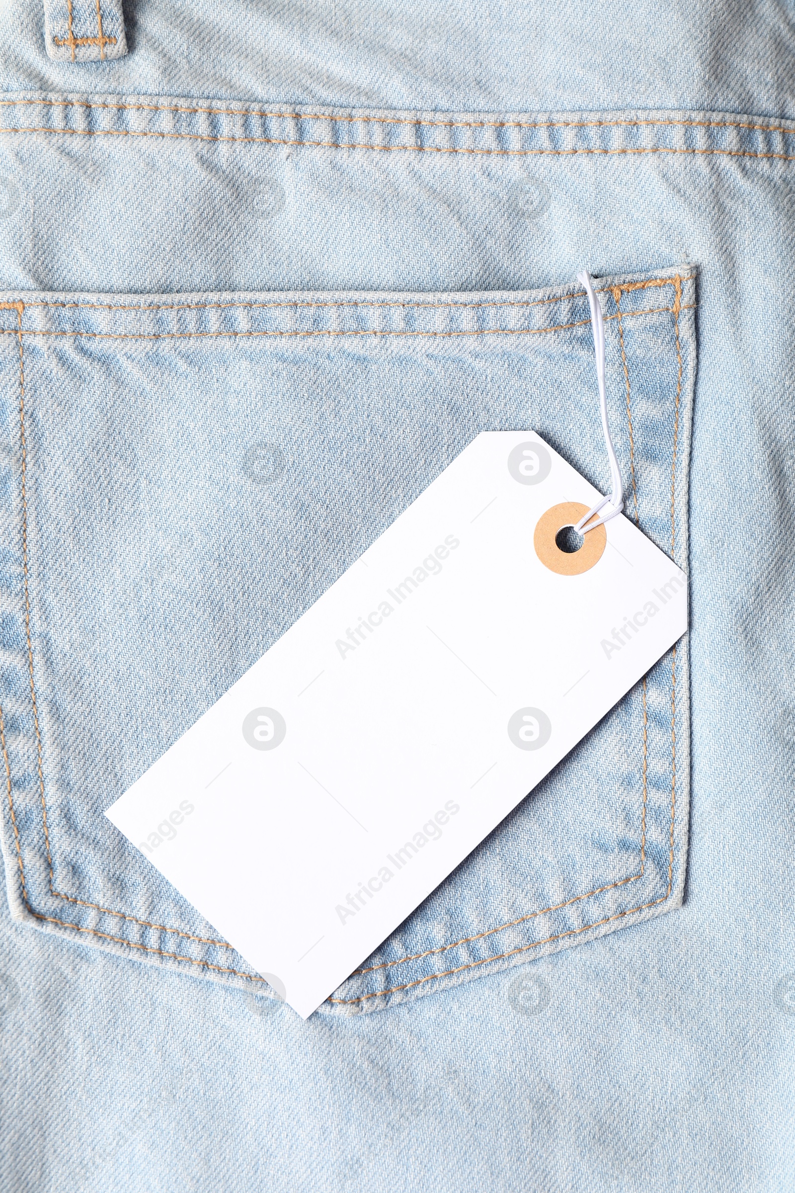 Cardboard tag on light blue jeans, top view Photo of Cardboard tag on light blue jeans, top view