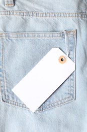 Photo of Cardboard tag on light blue jeans, top view