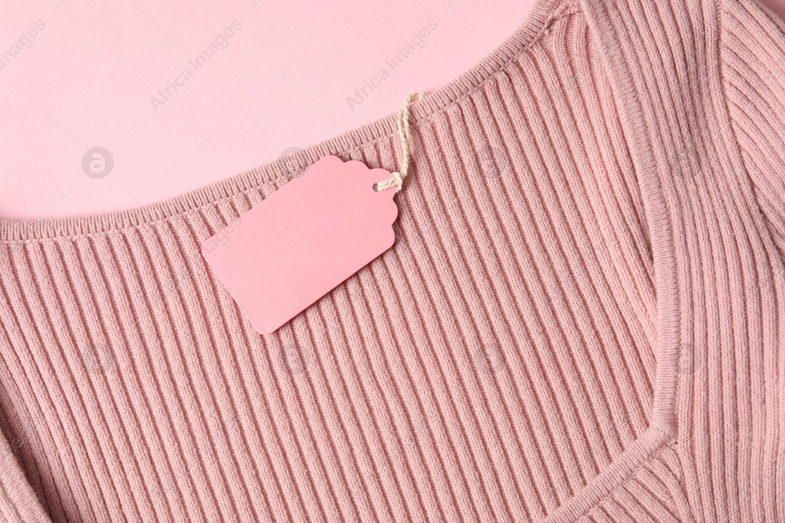 Color garment with tag on pink background, top view Photo of Color garment with tag on pink background, top view