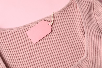 Photo of Color garment with tag on pink background, top view