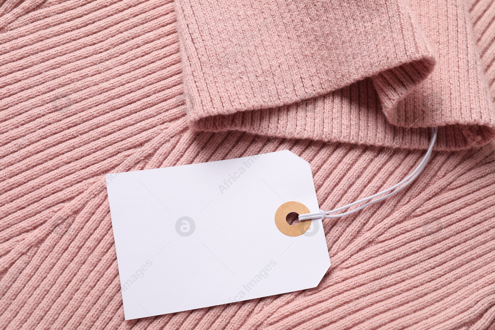 Cardboard tag on pink garment, top view Photo of Cardboard tag on pink garment, top view