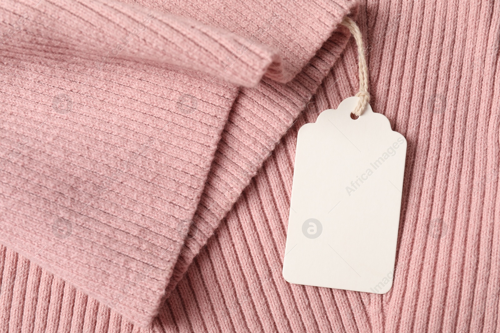 Cardboard tag on pink garment, top view Photo of Cardboard tag on pink garment, top view
