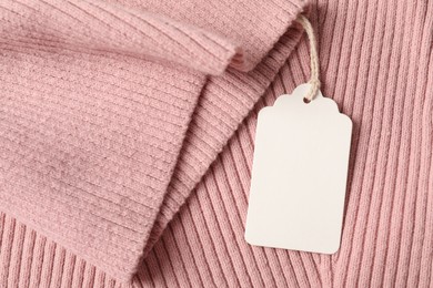 Photo of Cardboard tag on pink garment, top view