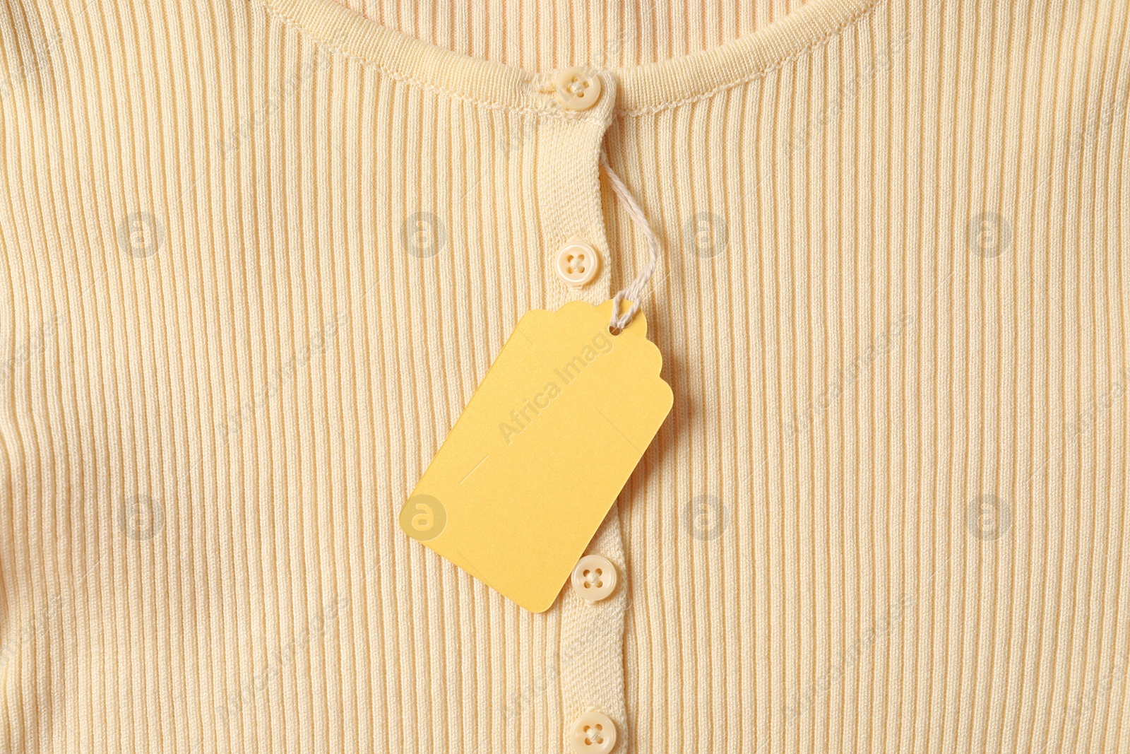 Cardboard tag on beige garment, top view Photo of Cardboard tag on beige garment, top view