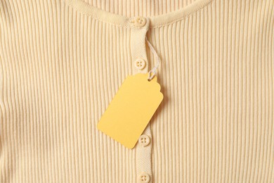 Photo of Cardboard tag on beige garment, top view
