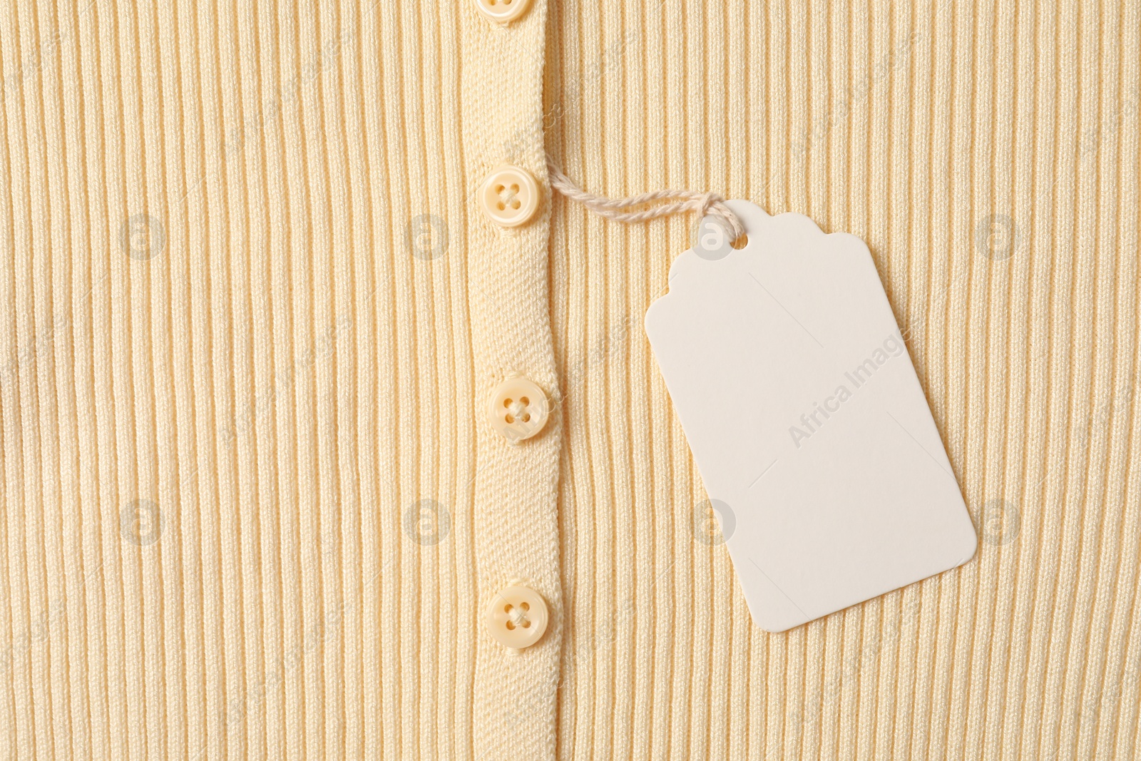 Cardboard tag on beige garment, top view Photo of Cardboard tag on beige garment, top view