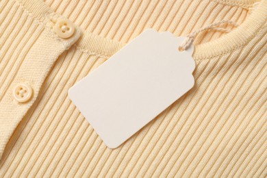 Photo of Cardboard tag on beige garment, top view