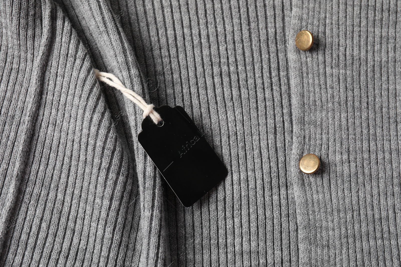 Cardboard tag on grey garment, top view Photo of Cardboard tag on grey garment, top view