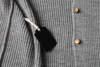 Photo of Cardboard tag on grey garment, top view