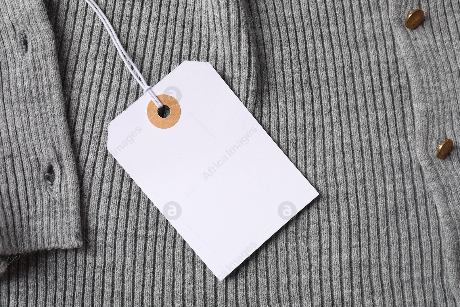 Cardboard tag on grey garment, top view Photo of Cardboard tag on grey garment, top view