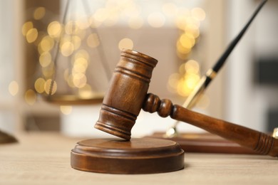 Photo of Judge's gavel on wooden table in office, closeup. Bokeh effect