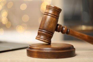 Photo of Judge's gavel on wooden table in office, closeup. Bokeh effect