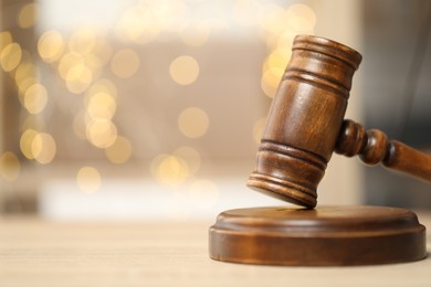 Photo of Judge's gavel on wooden table in office, closeup. Bokeh effect