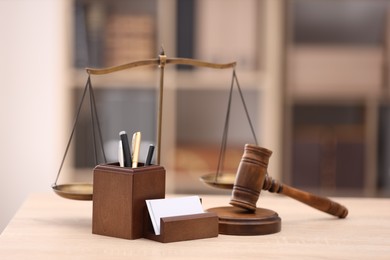 Photo of Judge's gavel, scales and stationery on wooden table in office