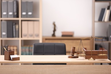 Photo of Judge's gavel, scales, stationery and document tray on table in office
