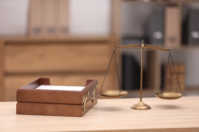 Photo of Scales of justice and document tray on wooden table in office
