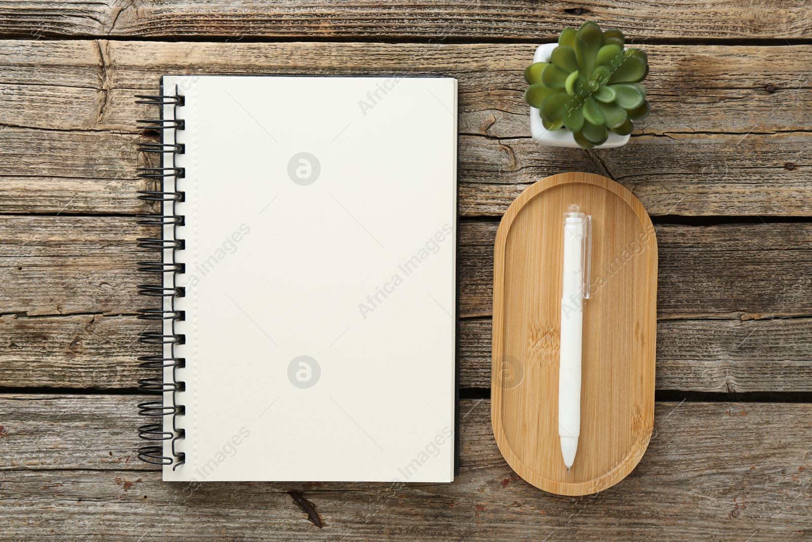 Photo of Notebook, pen and floral decor on wooden table, flat lay