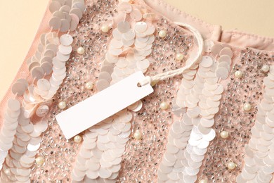 Photo of Stylish dress with tag on beige background, top view