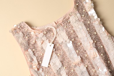 Photo of Stylish dress with tag on beige background, top view