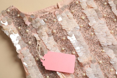 Photo of Stylish dress with tag on beige background, top view