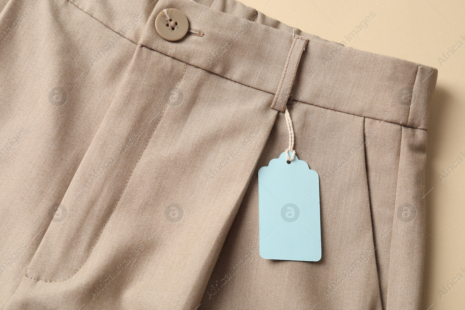 Pants with tag on beige background, top view Photo of Pants with tag on beige background, top view
