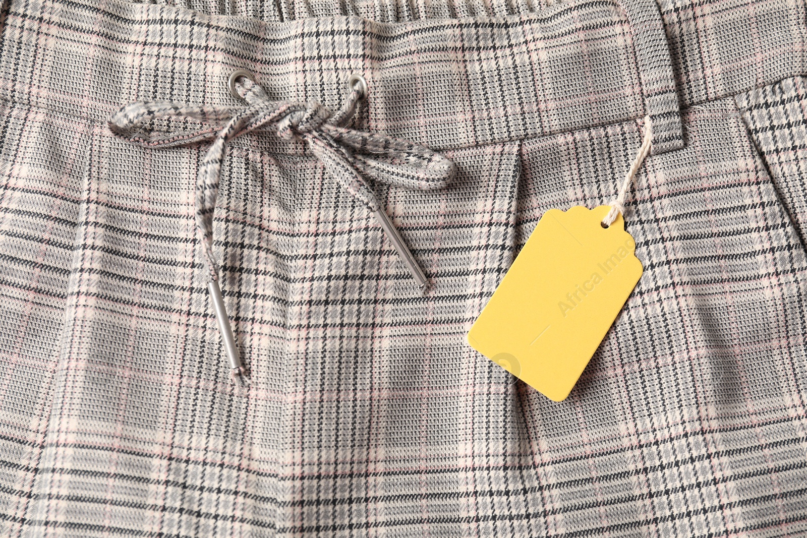 Cardboard tag on checkered pants, top view Photo of Cardboard tag on checkered pants, top view