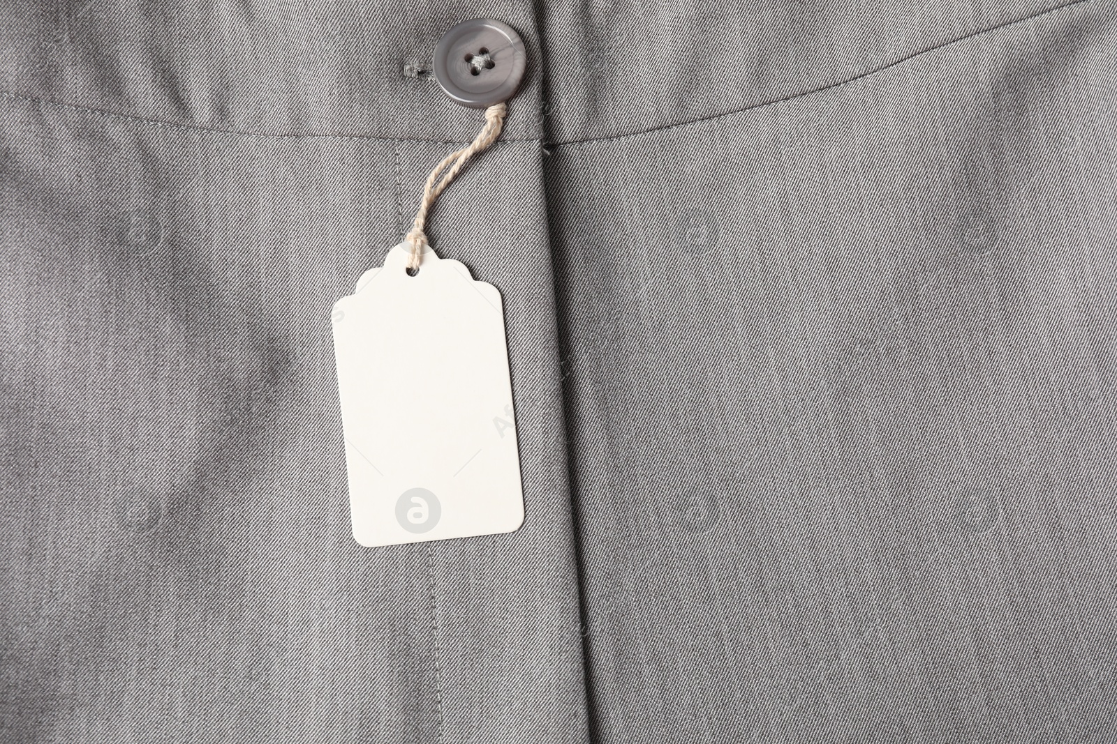 Cardboard tag on grey pants, top view Photo of Cardboard tag on grey pants, top view