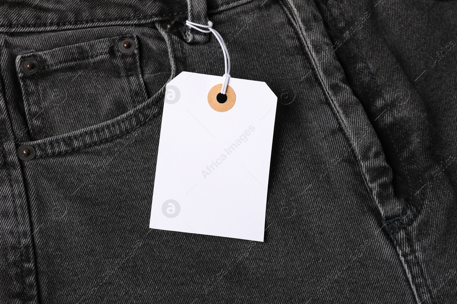 Cardboard tag on black jeans, top view Photo of Cardboard tag on black jeans, top view