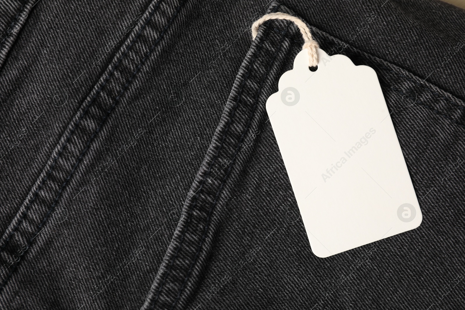 Cardboard tag on black jeans, top view Photo of Cardboard tag on black jeans, top view