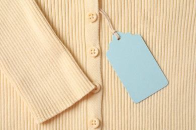Photo of Cardboard tag on beige garment, top view