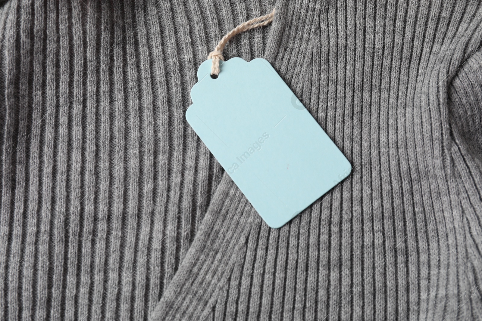 Cardboard tag on grey garment, top view Photo of Cardboard tag on grey garment, top view