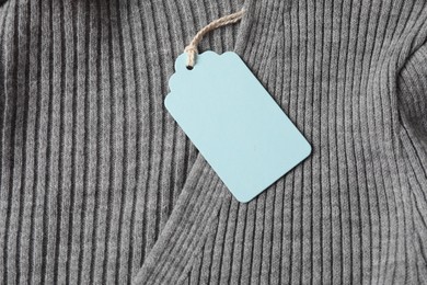 Photo of Cardboard tag on grey garment, top view