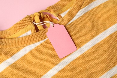 Photo of Color garment with tag on pink background, top view