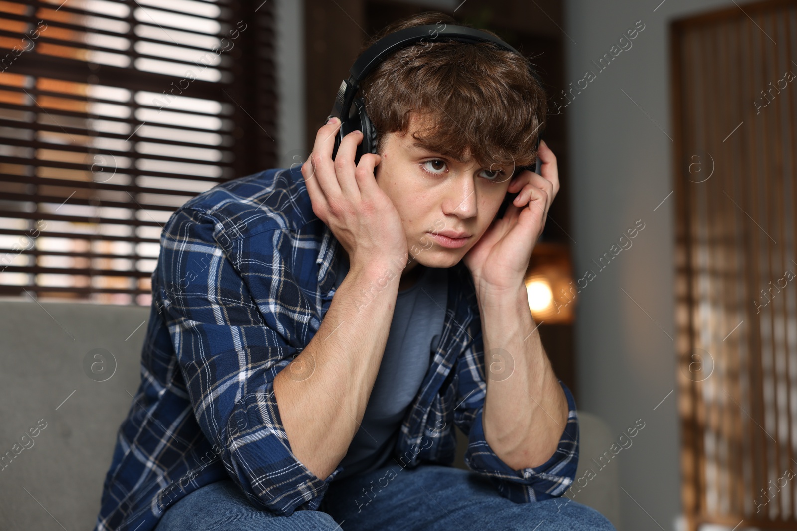 Teen problems. Upset teenage boy in headphones at home Photo of Teen problems. Upset teenage boy in headphones at home