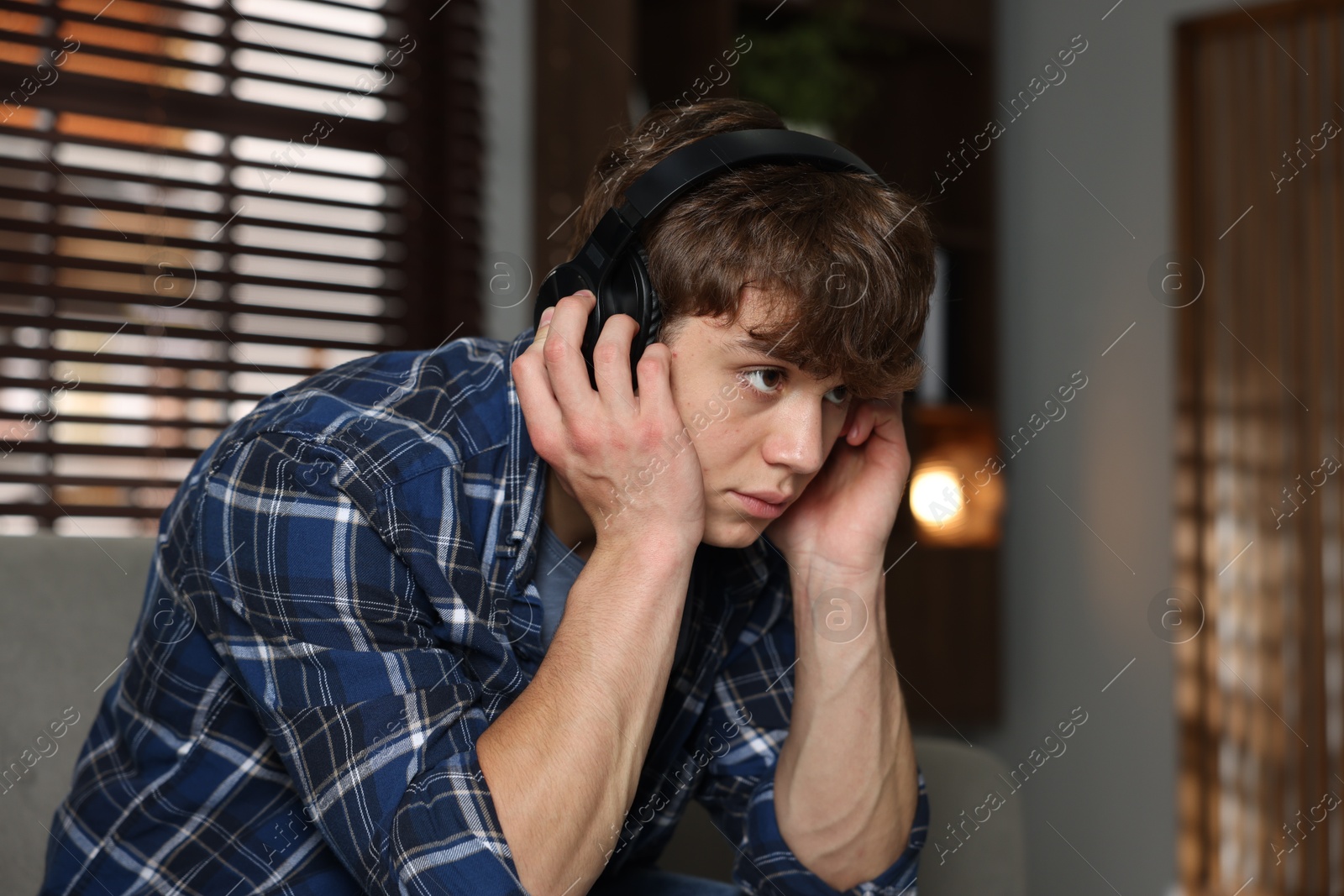 Teen problems. Upset teenage boy in headphones at home Photo of Teen problems. Upset teenage boy in headphones at home