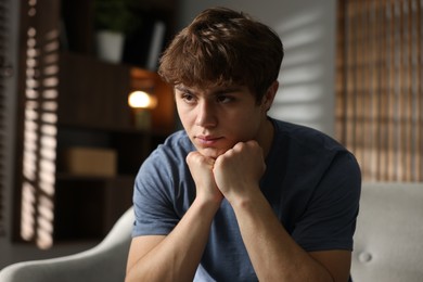 Photo of Teen problems. Upset teenage boy on sofa at home