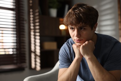 Photo of Teen problems. Upset teenage boy on sofa at home, space for text