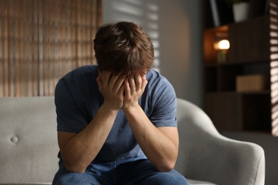 Photo of Teen problems. Depressed teenage boy on sofa at home