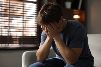 Photo of Teen problems. Depressed teenage boy on sofa at home