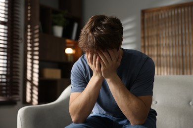 Photo of Teen problems. Depressed teenage boy on sofa at home