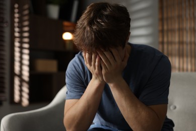 Photo of Teen problems. Depressed teenage boy on sofa at home