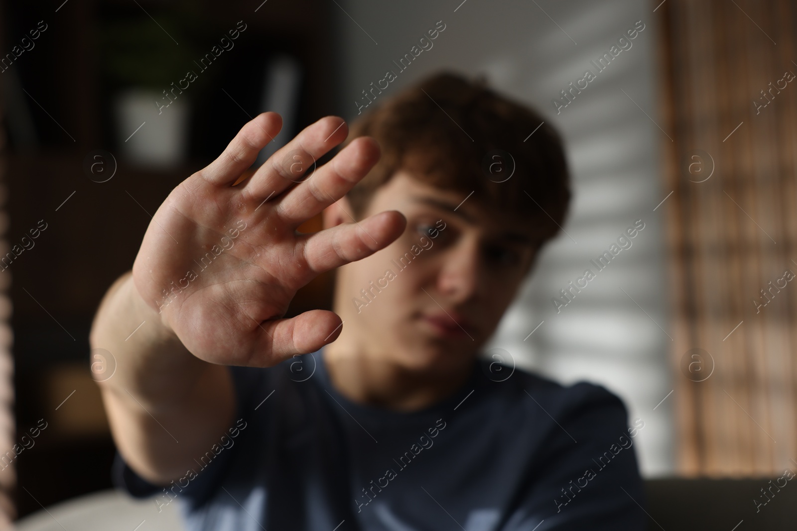 Teen problems. Upset teenage boy making stop gesture at home, selective focus Photo of Teen problems. Upset teenage boy making stop gesture at home, selective focus
