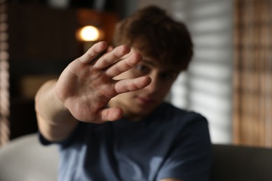 Photo of Teen problems. Upset teenage boy making stop gesture at home, selective focus